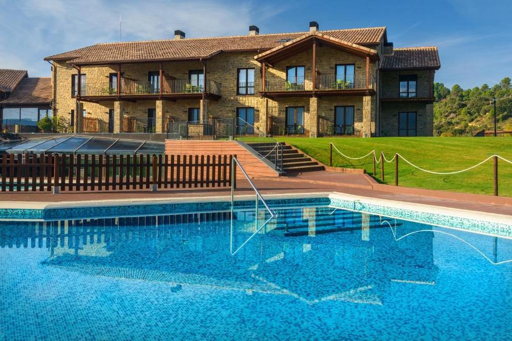Outdoor swimming pool and gardens at Hotel Agua de los Mallos