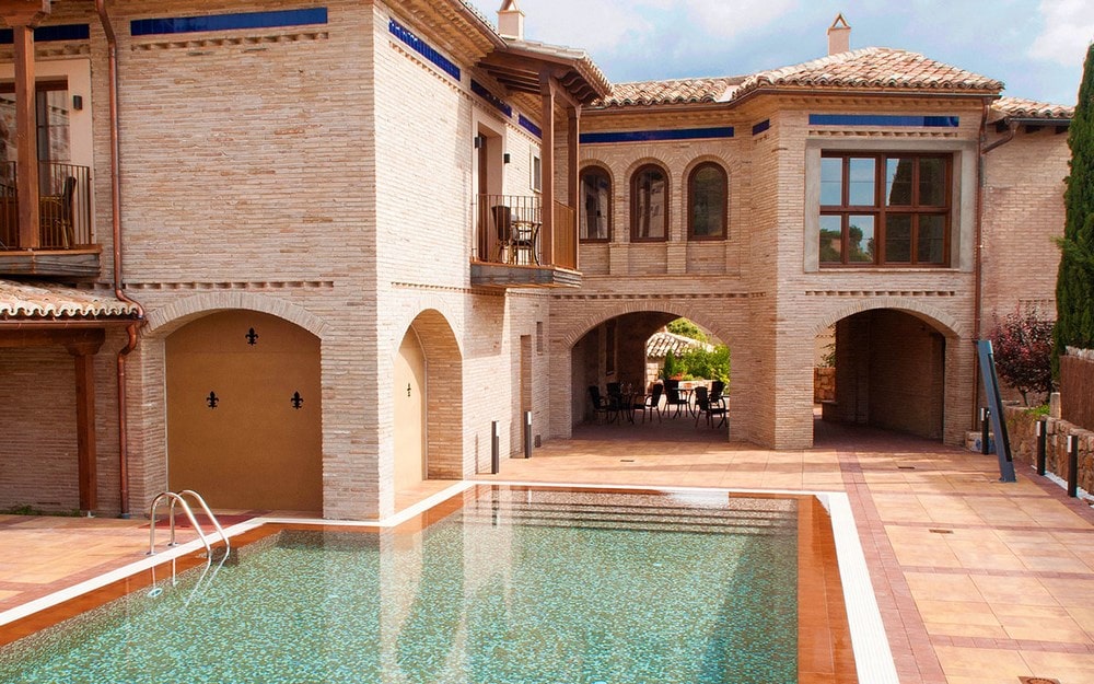 Outdoor pool and historic building at Hotel Villa de Alquézar